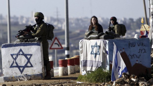 Israeli soldiers stand guard outside settlements in the occupied West Bank in March. 