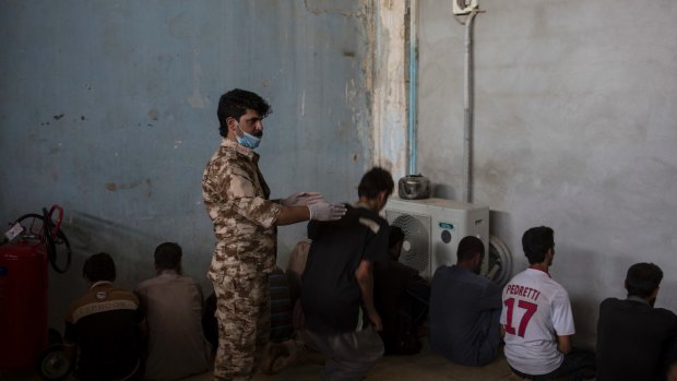 A Kurdish security officer orders a displaced man from Hawija to sit down inside a screening centre in Dibis, Iraq last week.