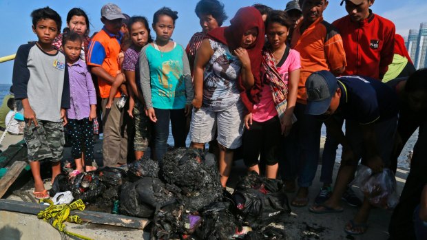 People at Muara Angke Port in Jakarta, Indonesia, inspect charred personal belongings of passengers on a ferry that caught fire.