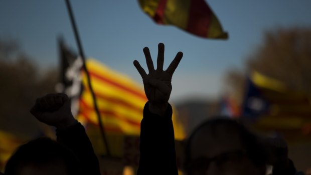 A pro independence demonstrator holds up four fingers symbolising the four bars of the Catalonian flag.