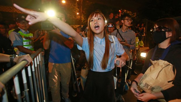 Newly elected Hong Kong lawmaker Yau Wai-ching shouts at police officers as thousands of people march in a Hong Kong street.