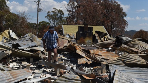 David Austin walks through the remains of his house, which was destroyed by a bushfire.