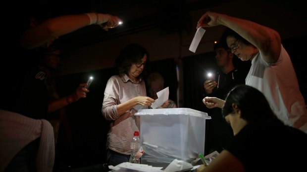 Volunteers start to count ballots during a blackout after the polling station closed at the La Llacuna school in Barcelona.