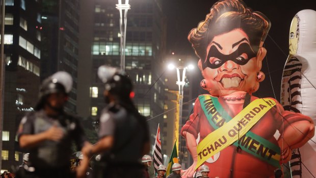 Police officers stand next to a large inflatable doll in the likeness of Brazil's President Dilma Rousseff wearing a presidential sash with the words in Portuguese "Goodbye dear" during a rally to celebrate her impeachment in Sao Paulo.