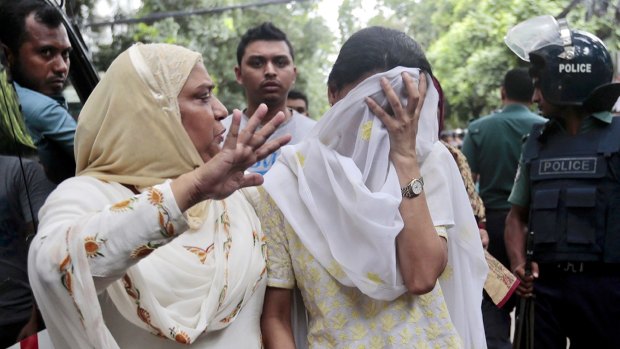 A relative tries to console Semin Rahman, covering face, whose son is missing after militants took hostages in a Dhaka cafe.