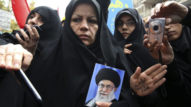 An Iranian demonstrator holds a portrait of the Supreme Leader Ayatollah Ali Khamenei, as another shows her hand with a slogan in support of the leader last month. 
