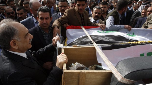 Iraqi Deputy Prime Minister Saleh al-Mutlaq (left) holds on to the coffins during the funeral of Sheikh Qasim al-Janabi and his son, Mohammad.