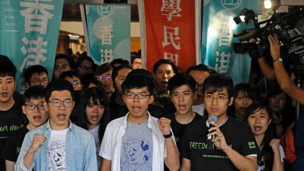 Hong Kong activists, from left to right front row, Nathan Law, Joshua Wong and Alex Chow chant slogans outside the high court in Hong Kong on Thursday.