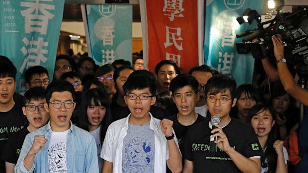 Hong Kong activists, from left to right front row, Nathan Law, Joshua Wong and Alex Chow chant slogans outside the high court in Hong Kong on Thursday.