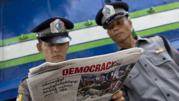 Police officers read a copy of the newspaper "Democracy Today" in Yangon on Wednesday. 