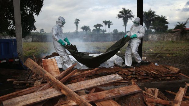 A team from the Liberian Ministry of Health unloads the bodies of Ebola victims onto a funeral pyre on Friday.