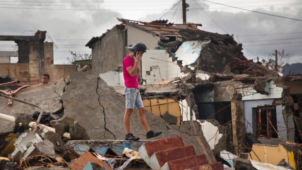 A man talks on his phone while searching for belongings amid the rubble of his home destroyed by Hurricane Matthew in Baracoa, Cuba.