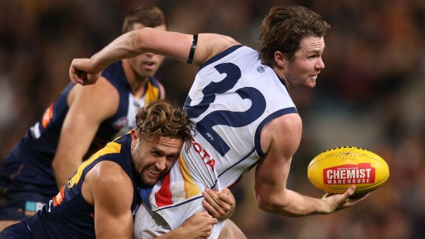 Patrick Dangerfield of the Crows looks to handball while being tackled by Mark Hutchings of the Eagles.