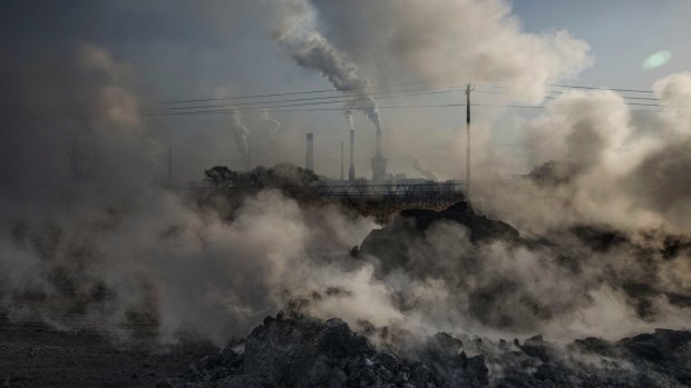 Smoke billows from a large steel plant as a labourer works at an unauthorised steel factory in Inner Mongolia, China.