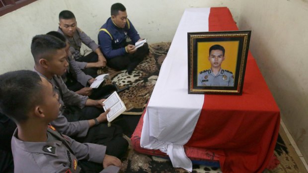 Police officers pray near the coffin of their slain colleague on Thursday.