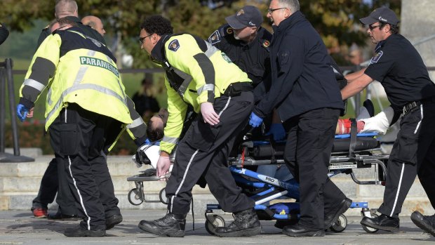 Paramedics and police pull a victim away from the Canadian War Memorial in Ottawa