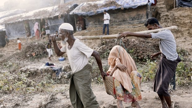 Family members carry a Rohingya woman suffering from a hip injury in a basket at a newly set-up refugee camp at Balukhali in Cox's Bazar, Bangladesh.