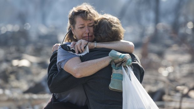 Casey Snow, left, embraces Susan Taylor Fellbaum as they look through their burnt home in Santa Rosa.