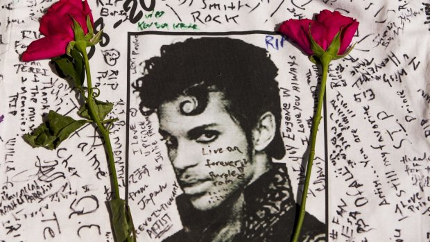 Flowers lay on a T-shirt signed by fans of singer Prince at a makeshift memorial place created outside Apollo Theatre in New York.