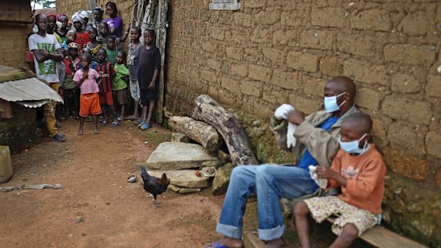 Sekou Sherif and his eight-year-old son Siafa, both with Ebola symptoms, don protective gear before being taken away for treatment by truck, in Guinea in November last year. 