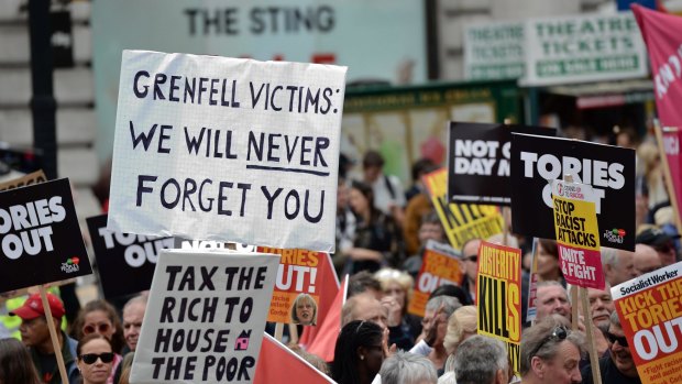 Demonstrators carry placards during the 'Not One Day More' march past Piccadilly Circus on July 1, calling for an end to the Conservative government and policies of austerity. 