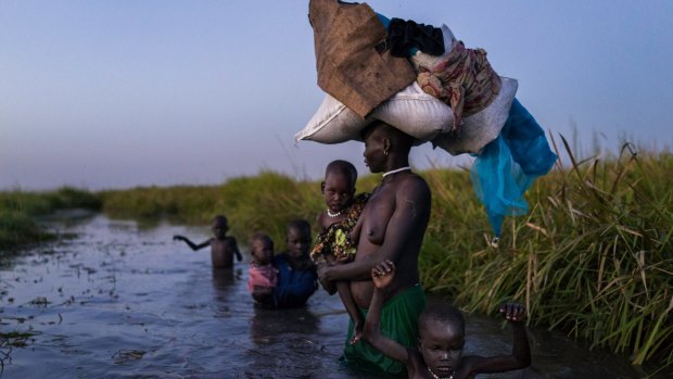 Showing at the festival: A woman with her five children walks back through cold swamps at dusk to her hiding place after receiving food. Kok Island, South Sudan, 2015. 