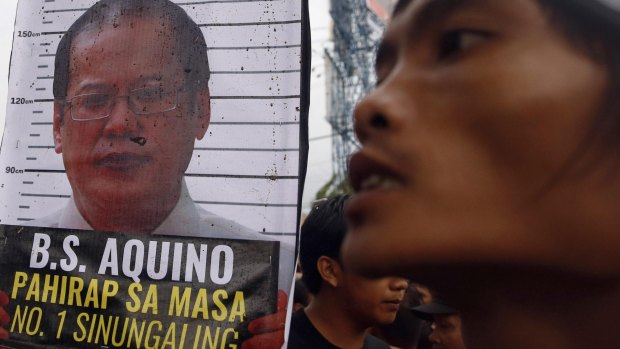 A placard containing an image of Aquino near a protester after demonstrators were blocked from marching towards Batasang Pambansa, where Aquino addressed the nation.