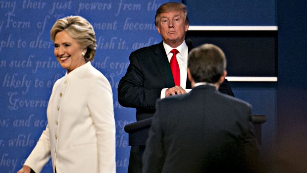 Donald Trump stands as Hillary Clinton exits the stage after the third presidential debate in Las Vegas.