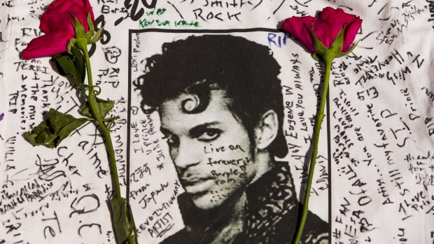 Flowers lie on a T-shirt signed by fans of singer Prince at a makeshift memorial place created outside Apollo Theatre in New York.