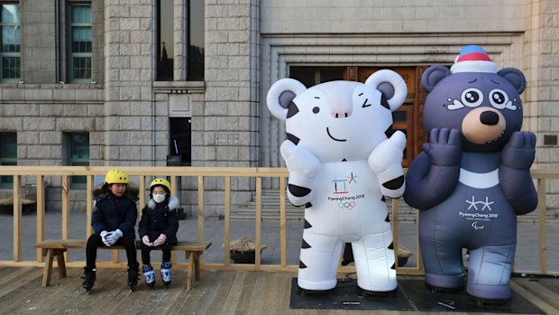 Children sit next to the 2018 Pyeongchang Winter Olympic Games' official mascots, a white tiger Soohorang, for the Olympics, 