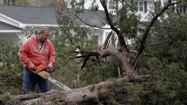 Cedar Lane, Virginia resident HR Whaley works to clear downed cedar trees on Wednesday. Governor Terry McAuliffe has declared a state of emergency in response to a powerful storm that left four dead.