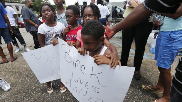 Children hold signs reading outside the store where Alton Sterling was shot and killed.