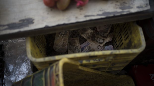 A crate filled with 100-bolivar notes sits under the counter of a fruit stand in Caracas.