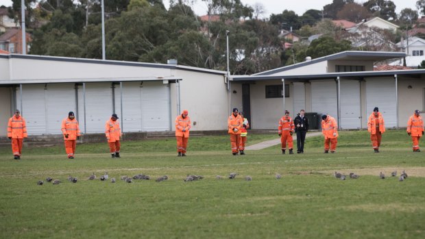 Emergency workers do a line search at Dunstan Reserve in West Brunswick. 