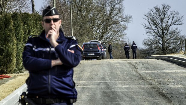 A gendarme stands guard near the site where the thieves attacked the vans.