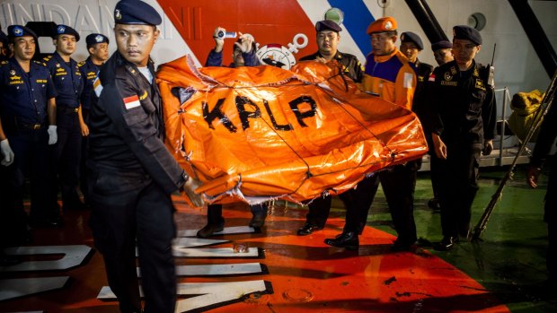 Indonesian Sea and Coast Guard officers on Tuesday carry remains of seats from the AirAsia flight.
