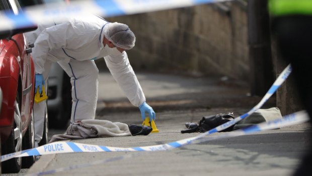 Forensic police examine shoes and a handbag at the scene.