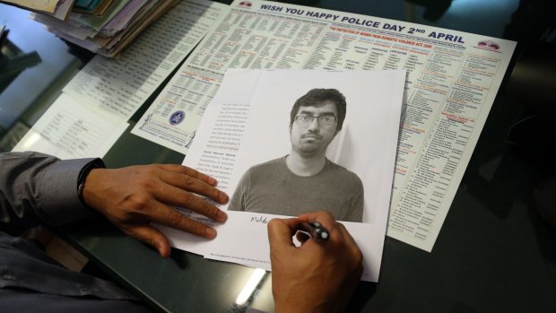 A police officer writes on a photograph of arrested tweeter Mehdi Masroor Biswas.