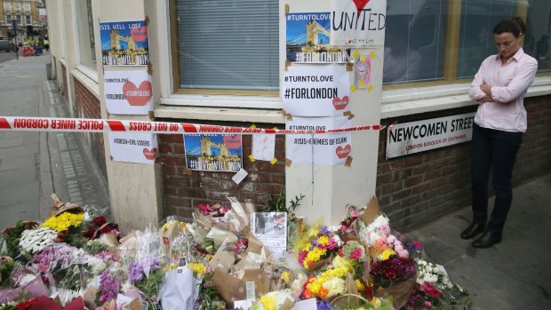 A woman stands next to floral tributes in the London Bridge area.