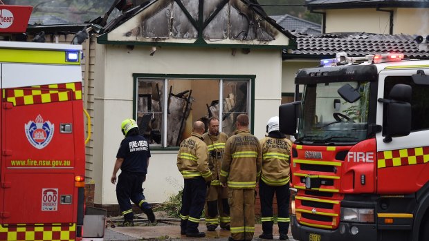 NSW fire and rescue stand in front of a destroyed home on St George's Road in Penshurst.