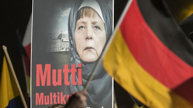 A banner reading 'Mum multiculti' and depicting a manipulated image of German Chancellor Angela Merkel is carried by a protester behind the German flag as thousands of people join a protest in Erfurt, central Germany, on Wednesday. 