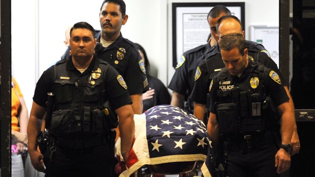 Palm Springs police officers carry the body of one of their colleagues to a hearse.