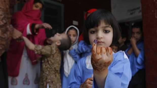 A Pakistani student shows her finger marked with ink to confirm she received a polio vaccine in Peshawar in April.