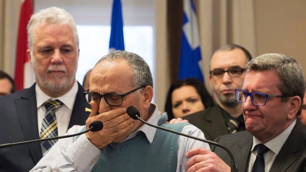 Mohamed Labibi, president of the Islamic cultural centre, is comforted by Quebec Premier Philippe Couillard, left, and Quebec City mayor Regis Labeaume, right, during a news conference.