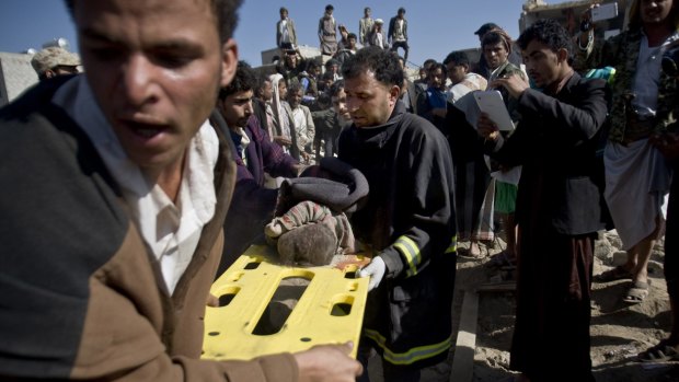 Yemenis carry the body of a child from houses hit by Saudi air strikes near Sanaa Airport on March 26.