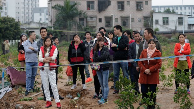 People stand watch behind a police line as rescuers searching for survivors in Shenzhen.