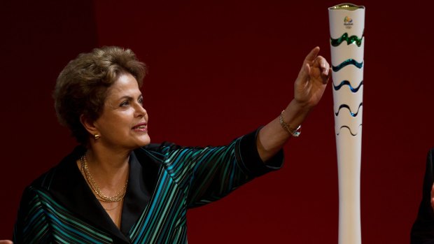 Dilma Rousseff inspects the Olympic torch as it's presented during a ceremony ahead of the 2016 Rio Olympic Games in Brasilia, Brazil. 