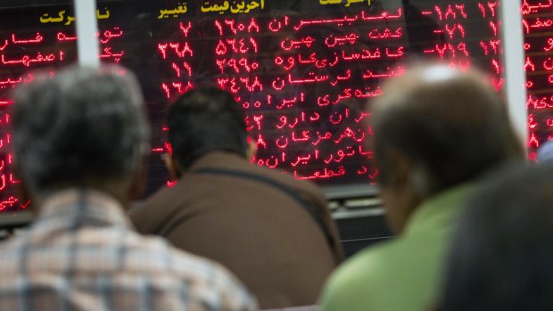 Visitors sit in a viewing area and look at financial information displayed on digital screens at the Tehran Stock Exchange in Tehran, Iran.