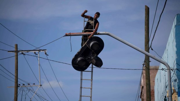 A worker dismantles a traffic light before the arrival of Hurricane Matthew in Santiago, Cuba.