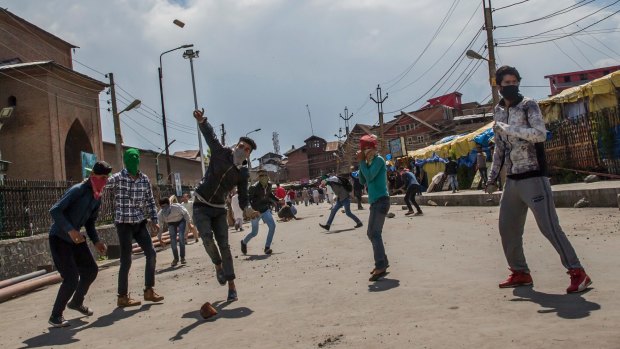 Masked Kashmiri protesters throw rocks and bricks at Indian government forces in Srinagar, Kashmir, on Friday.